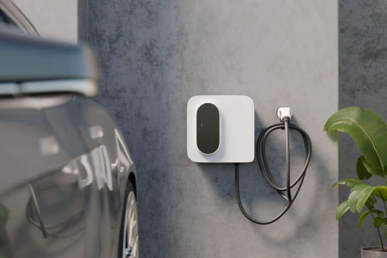 Wall-mounted EV charger on a concrete garage wall with electric car. Tidy cable loop and plant detail. Photorealistic 3D render with copy space for home charging and e-mobility.